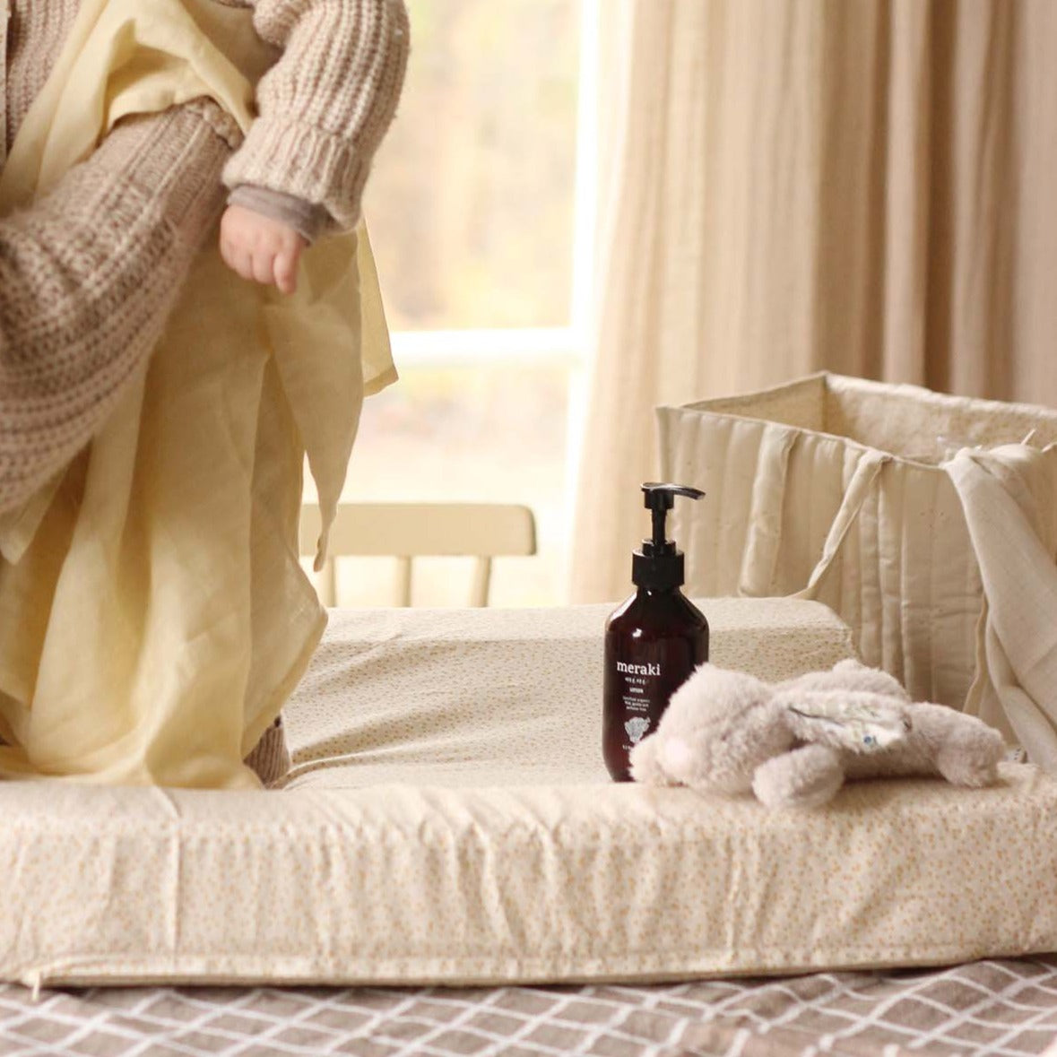 A baby changing on top of a changing cushion in daisy meadow print