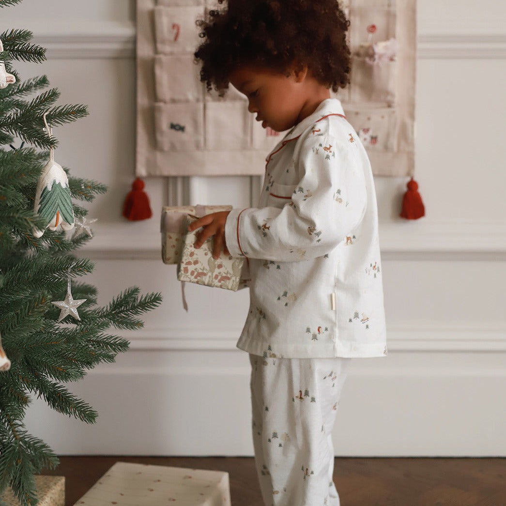 A boy on pyjamas winter ski opening a gift box