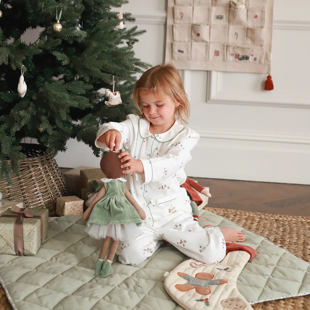 A girl on winter ski pyjamas playing with ballerina doll