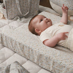 Baby lying on a nature trail covered changing cushion