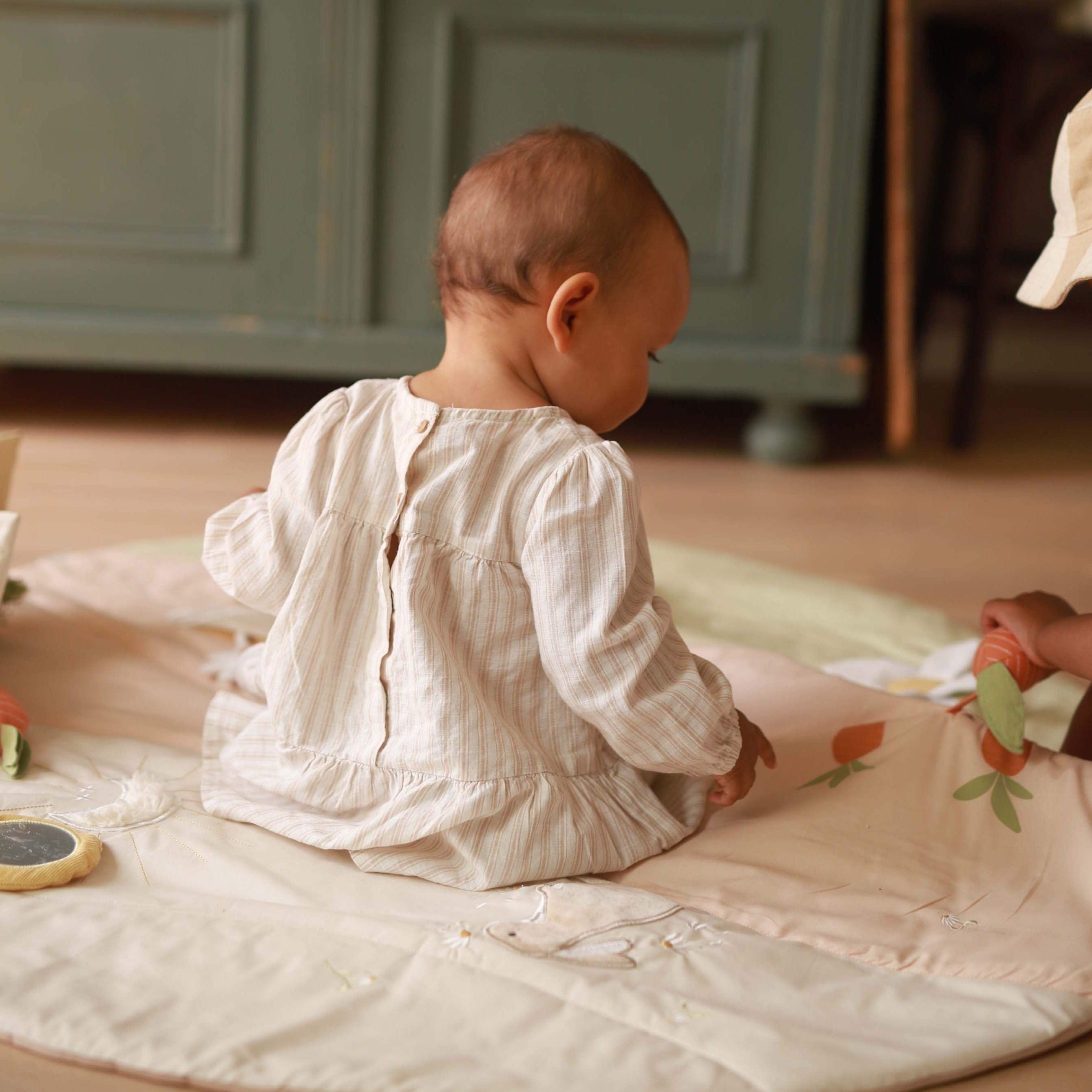 Baby playing with pull out carrot on activity mat chamomile