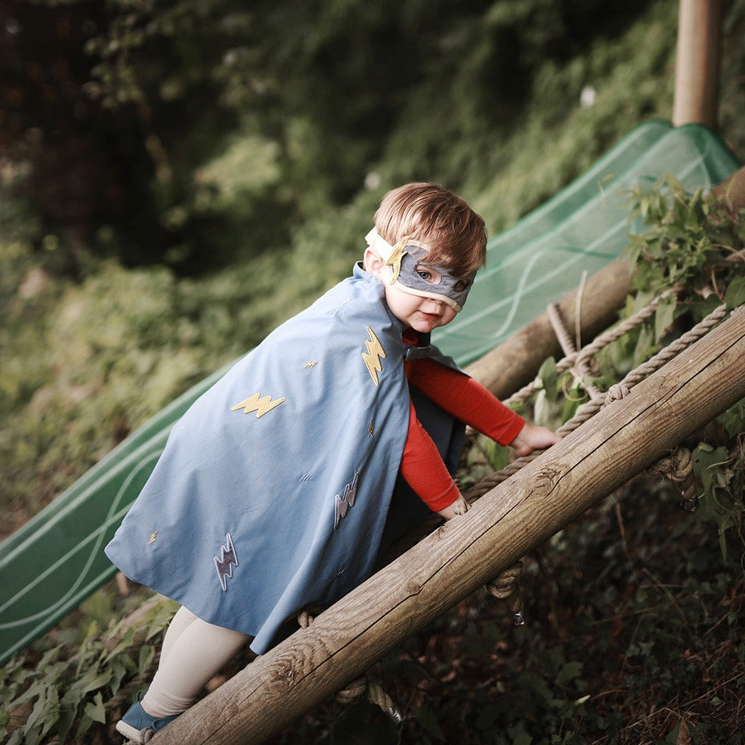 boy wearing 3 piece blue and yellow superhero set climbiing